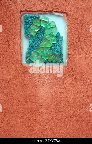 A figure 2 made from green coloured glass set into a rectangular panel on an orange painted exterior wall Stock Photo