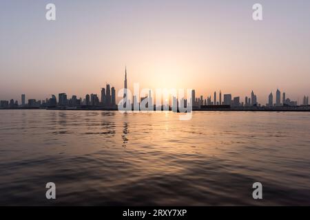 Dubai, United Arab Emirates, April 28th, 2017. The sun dips behind the city's towering skyscrapers, casting a mesmerising silhouette along the tranqui Stock Photo