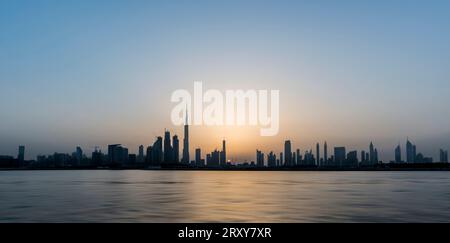 Dubai, United Arab Emirates, April 28th, 2017. Sunset in Dubai, silhouetted cityscape along water canal, sun setting behind skyscrapers - NL Stock Photo