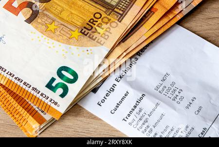 A foreign exchange receipt with fifty Euro bank notes on top. Holiday, travel money, money exchange concept. Stock Photo