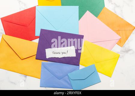 Colored envelopes and a thank you note on a marble kitchen counter in a top view Stock Photo