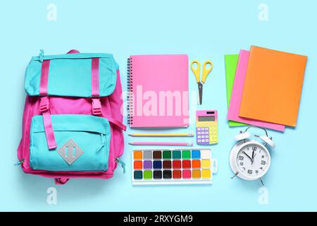 Stylish school backpack with different stationery on blue background Stock Photo