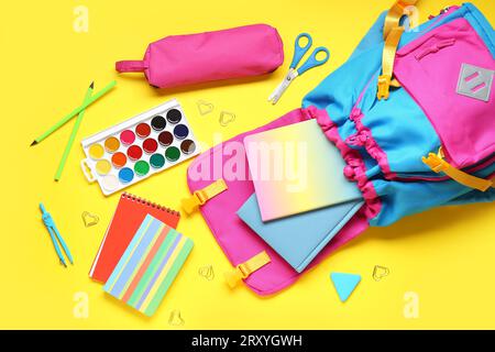 Composition with stylish school backpack and different stationery on yellow background Stock Photo