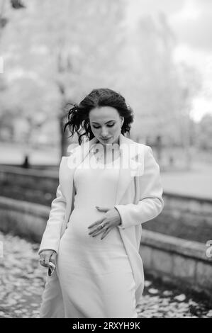 Pregnant woman in a coat in an autumn park Stock Photo