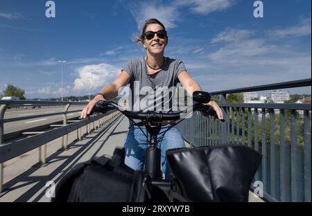 Woman with electro cargo bike biking with bags and baggage on cycleway bikeway with cargo-bike bicycle cycle Stock Photo