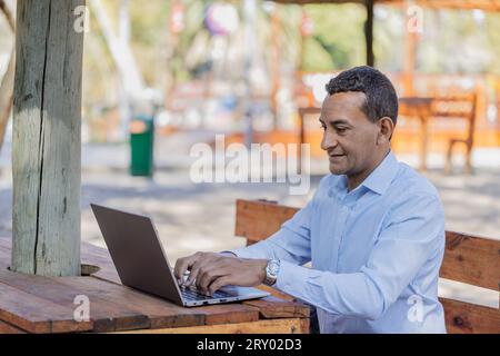 Young Latino man using a laptop outdoors. Stock Photo