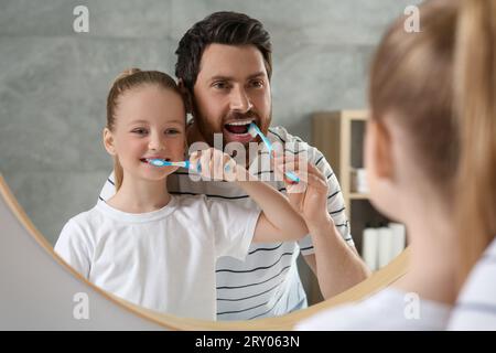 Father and his daughter brushing teeth together near mirror in bathroom Stock Photo