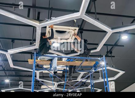 Electrician repairing air conditioner ceiling type in the office. Stock Photo
