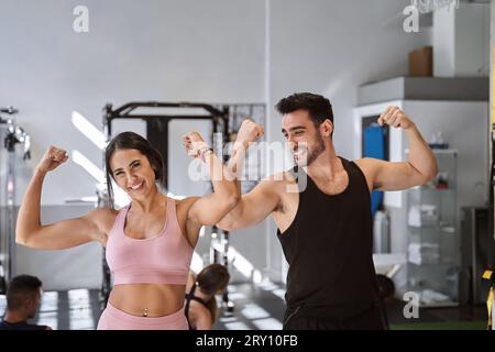 Happy fitness people showing their muscles after training in the gym. Sports concept. Stock Photo