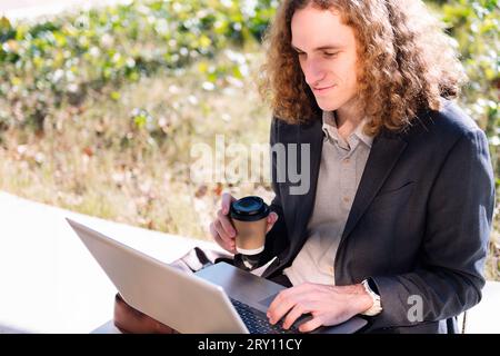 smiling businessman working outdoors with a laptop Stock Photo