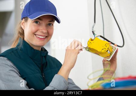 happy female builder with screwdriver fixing socket indoors Stock Photo
