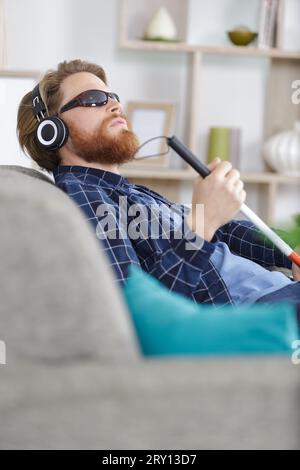blind man on a sofa using headphones Stock Photo