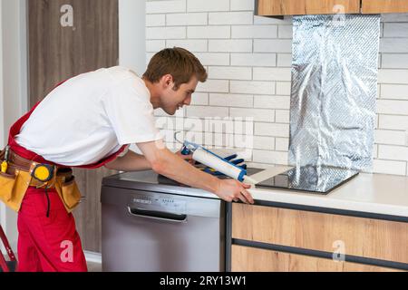 craftsman installs hob in kitchen. Household Appliance Installation Services Concept Stock Photo