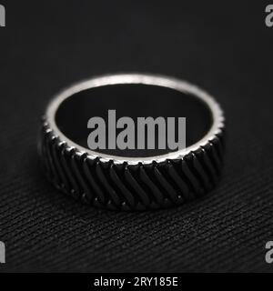 closeup shot of a circular platinum ring with a neatly cut design isolated in a black background Stock Photo