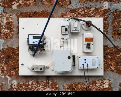 an electrical power outlet with wired cable connections, switches , fuse and electricity voltage reading meter on the wall Stock Photo