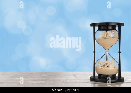 New 2024 Year Concept. Sand Falling in Hourglass Taking the Shape from 2023 to 2024 year on a wooden table. 3d Rendering Stock Photo