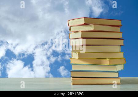 Stack of books with blue sky and clouds background, inspiration,imagination,fantasy,literature,reading, learning concept Stock Photo
