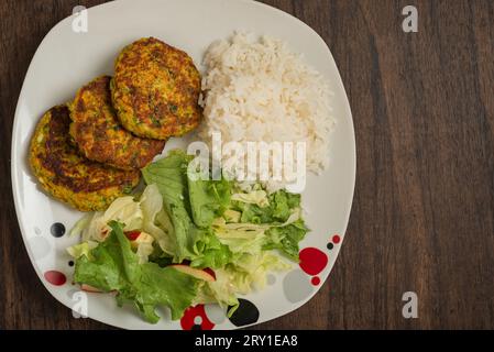 Oatmeal fritters with vegetables and white rice served on a plate on a wooden table. Healthy food. Stock Photo