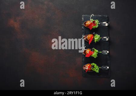 Molecular modern cuisine galantine duck in spoons on stone and rusty background. Top view. Stock Photo