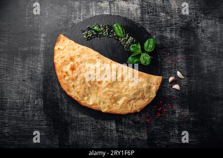 Traditional Italian pizza calzone with ingredients on a stone and dark ...