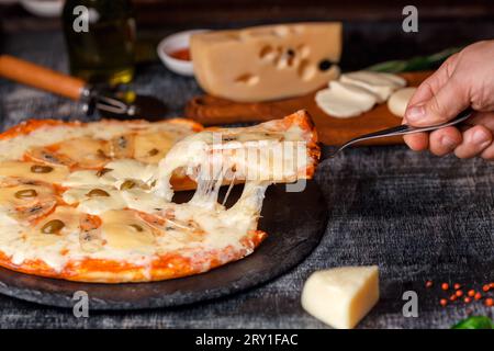 Italian pizza with different sorts of cheese on a stone and a black scratched chalk board. Italian traditional food. Top view. Stock Photo