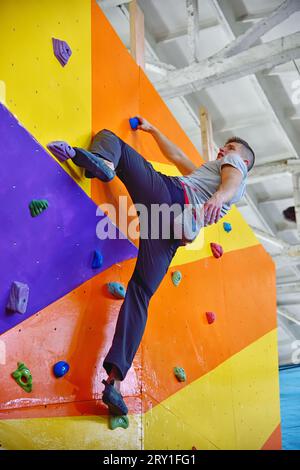 Free climber man climbing on color practice wall. Extreme and healthy lifestyle concept. Stock Photo