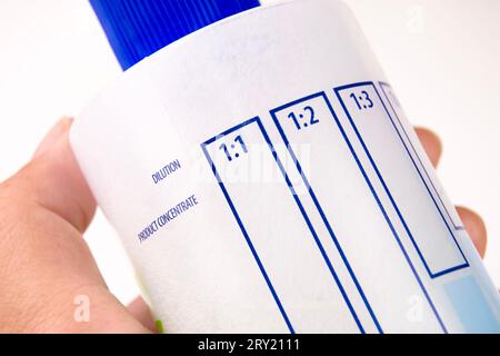 Close up a dilution ratio label of concentrated liquid chemicals on plastic bottles, human hand holding a plastic bottles for liquid chemicals. Stock Photo