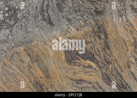 Background pattern of brown-colored granite in oblique unstructured wavy lines. Natural stone with gray and brown gradient. Dark spots in the stone Stock Photo