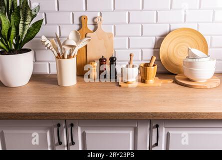 A set of various kitchen tools, utensils made of environmentally friendly materials on the kitchen countertop, a white brick wall. Eco-interior Stock Photo