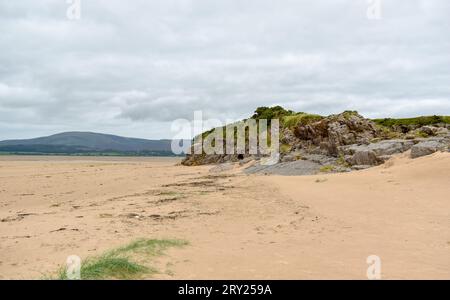 A partial view of the sandy and rocky coastline near Kirkby-In-Furness at low tide, with fells in the distance. Stock Photo