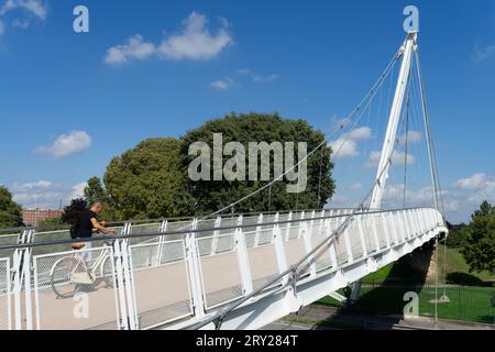 Man on bicycle crosses a suspension bridge over a busy street in downtown Padua. The bridge connects the riverbank with a public park, an ideal place Stock Photo