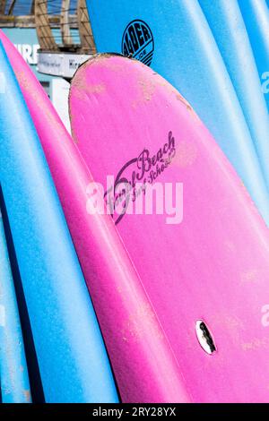 Colourful surfboards stacked and available to hire at the surf hire shop at Fistral Beach in Newquay in Cornwall in England in the UK. Stock Photo