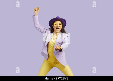 Photo of adorable cool young lady wearing in hat and glasses in a cowgirl position with empty space isolated purple color background Stock Photo