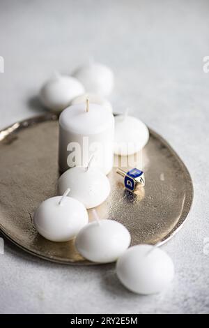 From above of celebration of Jewish light festival with ivory colored scented candles blue Hanukkah dreidel and cute spinning top on plate in daylight Stock Photo
