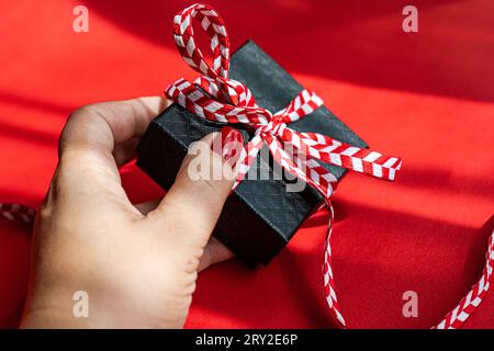 Crop anonymous female with small present box in daytime holiday on red background Stock Photo