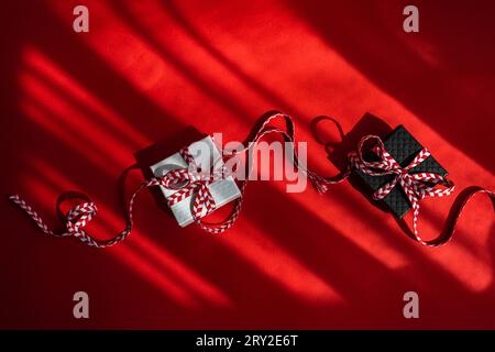 From above small colored cardboard boxes with red bow placed on red background Stock Photo