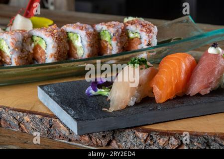 From above of delicious uramaki sushi and nigiri sushi together with sashimi in small bowls on wooden background Stock Photo