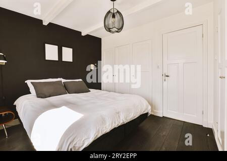 Interior of modern spacious bedroom with comfortable bed by black wall and white doors in contemporary apartment Stock Photo