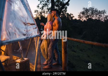 Full length of male and female standing together on terrace near wooden railing and enjoying evening time Stock Photo