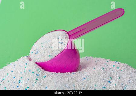 Washing powder in a plastic spoon on a green background. High quality photo Stock Photo
