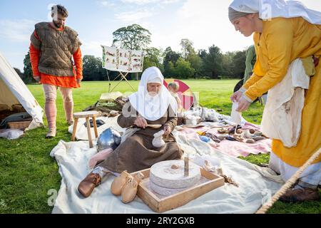 Viking woman grinds grist into flour whilst celebrating 1100 years of the ancient “cyty” of Thelwall Stock Photo