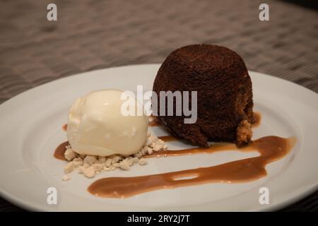 On a white plate, a perfect pairing: creamy vanilla ice cream alongside warm, caramelized malva pudding Stock Photo
