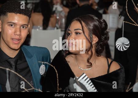 At prom, a young couple sits at a beautifully decorated table, lost in a world of elegance and romance. Stock Photo