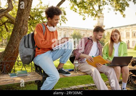 University students working on homework or creative project at campus outdoors Stock Photo