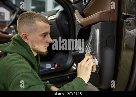 Car detailing process, closeup male worker cleaning door with brush Stock Photo