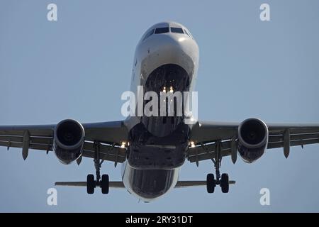 A large jet airliner, with the landing gear down, is shown during final approach or takeoff just before flying over outside an airport. Stock Photo