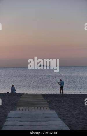 Couple at the end of the walkway on the sand by the sea sunrise Stock Photo
