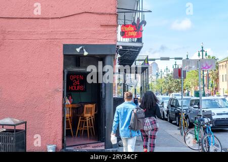 NEW ORLEANS, LA, USA - MARCH 26, 2023: Pedestrians pass the open door of the Voodoo Lounge on Rampart Street in the French Quarter Stock Photo