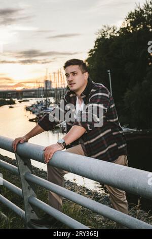man caucasian model millionaire yachtsman in a shirt with a watch on his wrist, stands on the pier of the yacht club at sunset Stock Photo