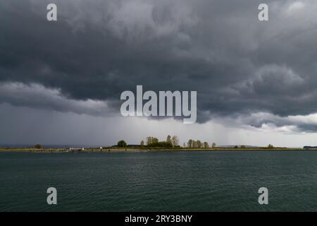 Storm clouds roll across Jetty Island in fall as wind ripples the water Stock Photo